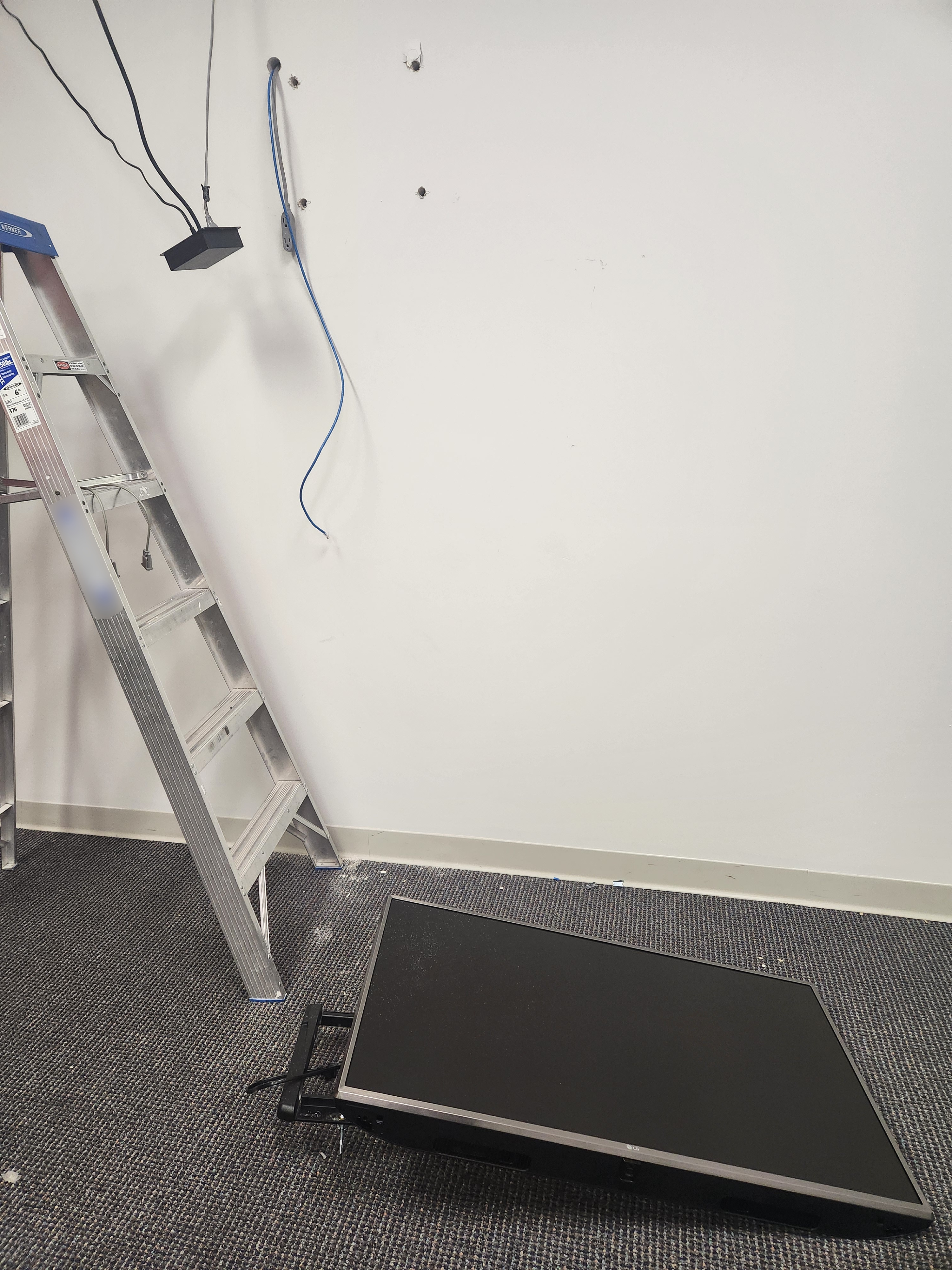 A flatscreen TV on the ground next to a ladder